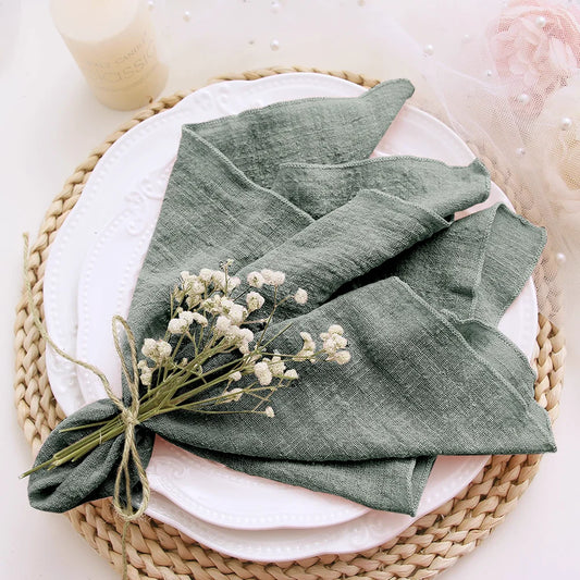 Green folded napkin on a white plate with baby's breath flowers, placed on a woven mat.