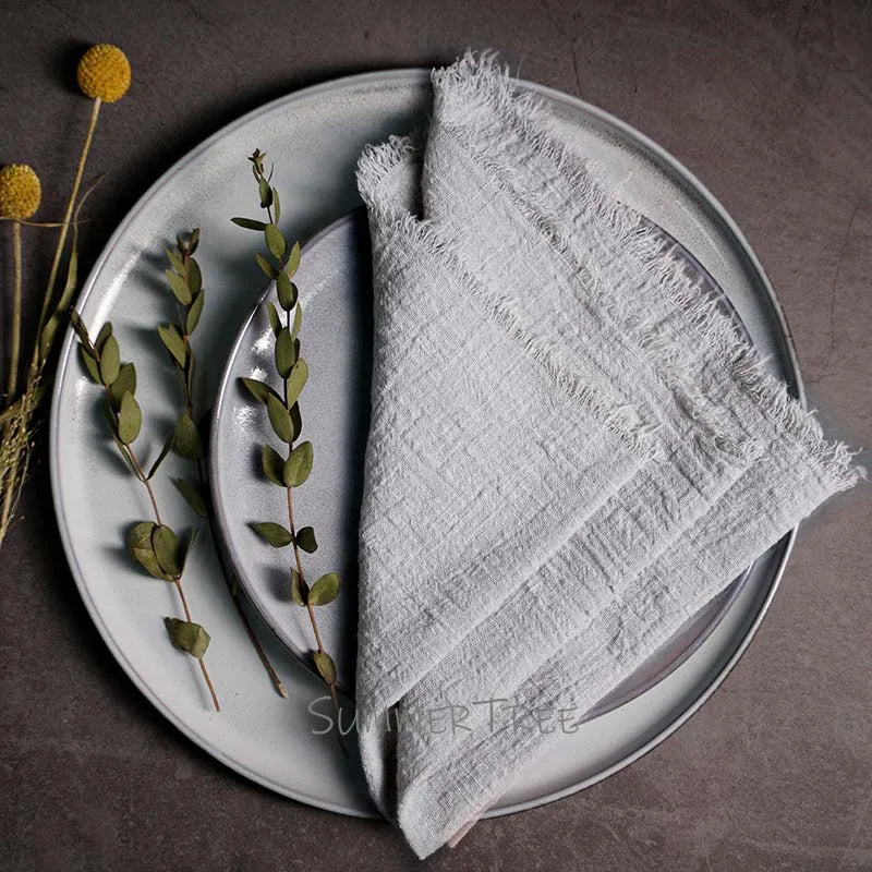 White napkin on a gray plate with greenery and flowers on a dark surface