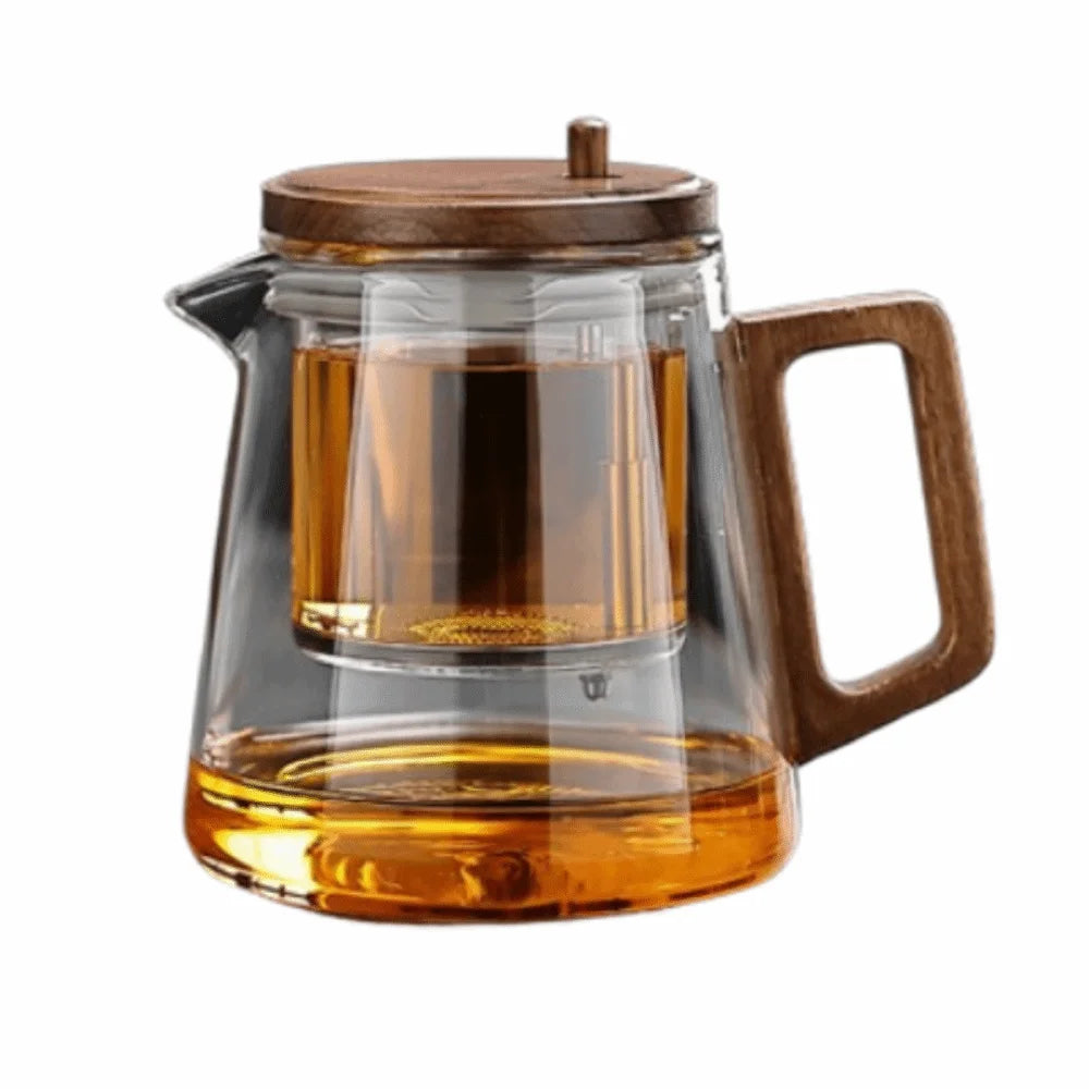 Clear glass teapot with wooden lid and handle filled with tea on a white background