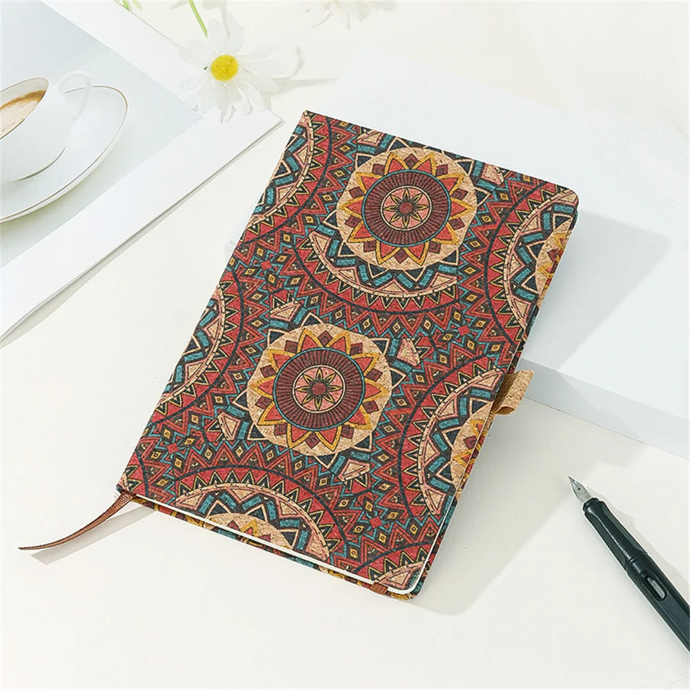 Notebook with a colorful mandala design on a white surface with a cup and pen.