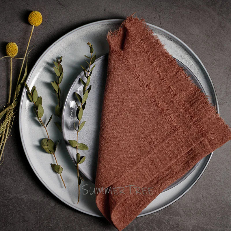 Brown napkin on a gray plate with greenery, on a dark surface.