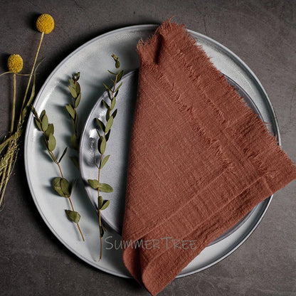 Brown napkin on a gray plate with greenery, on a dark surface.