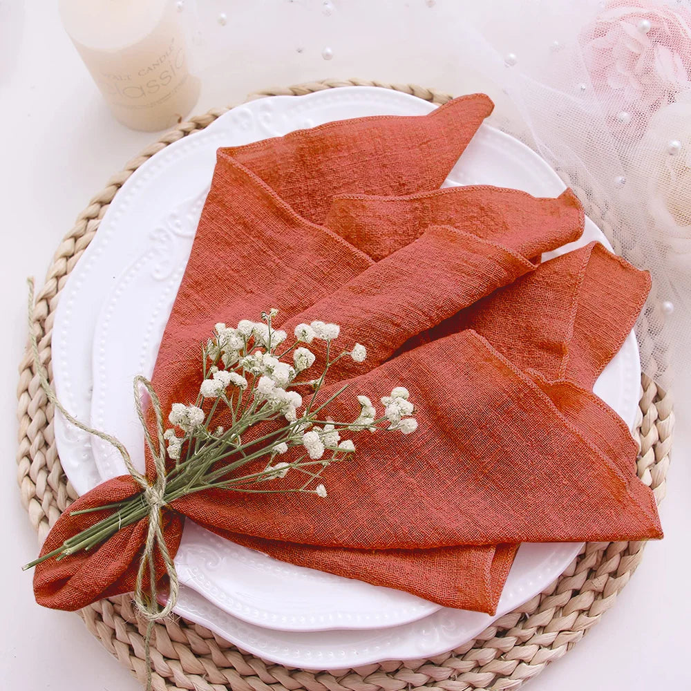 Red napkin folded on a white plate with small white flowers, placed on a woven placemat.