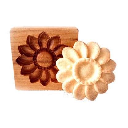 Wooden flower-shaped mold next to a soap bar with a similar shape on a white background